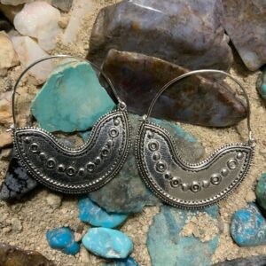 Ornate earrings displayed on natural rocks.