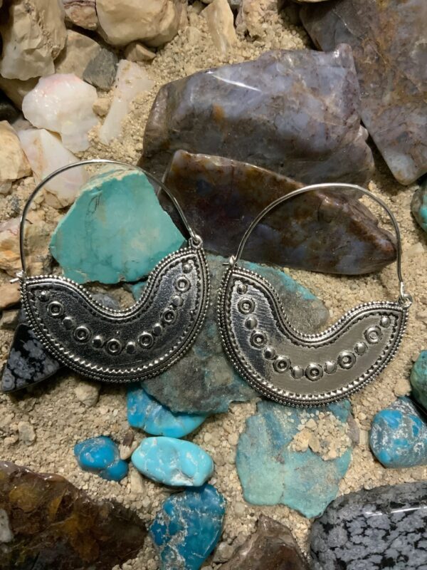 Ornate earrings displayed on natural rocks.
