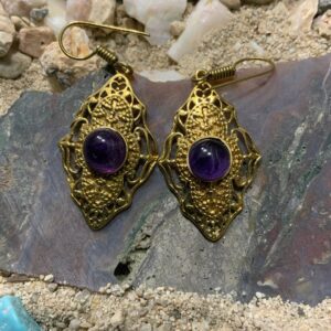 Intricate gold earrings on rocky surface