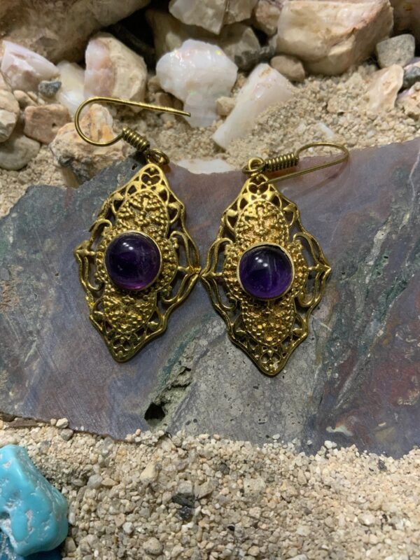 Intricate gold earrings on rocky surface