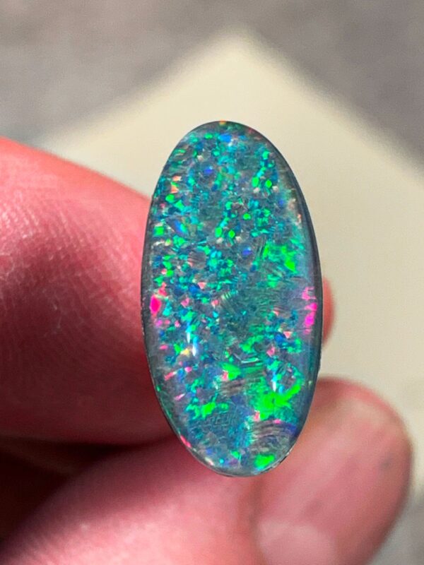 Colorful opal gemstone held by fingers