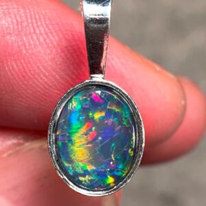 Hand holding colorful opal pendant