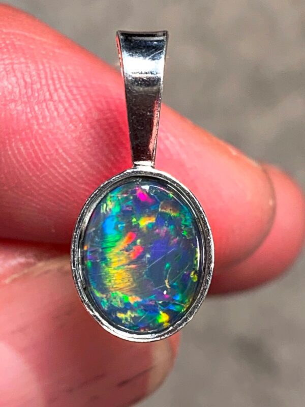 Hand holding colorful opal pendant