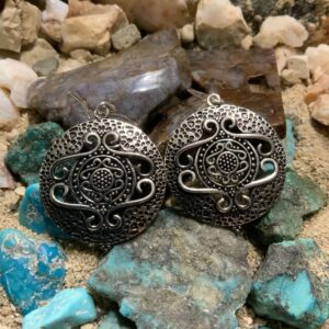 Intricate silver earrings displayed on rocks