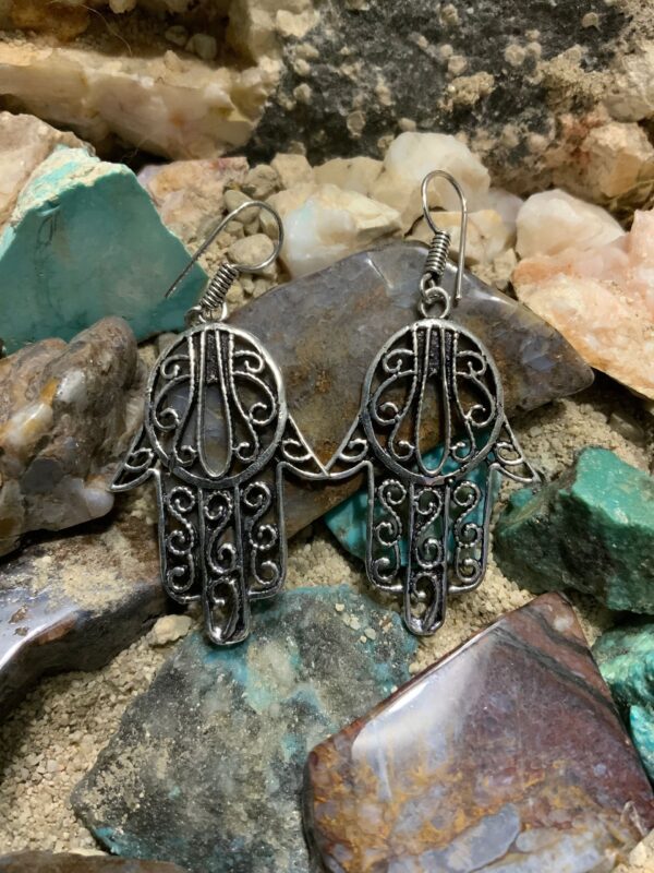 Hamsa earrings on stone background