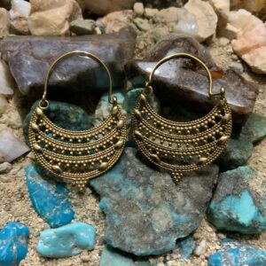 Gold earrings on colorful stone background