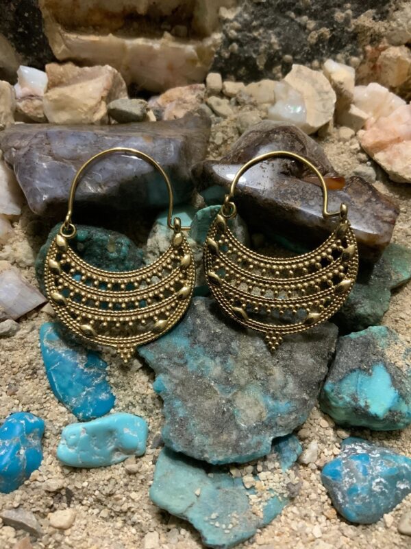 Gold earrings on colorful stone background