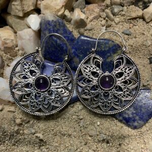 Decorative earrings placed on natural stone backdrop