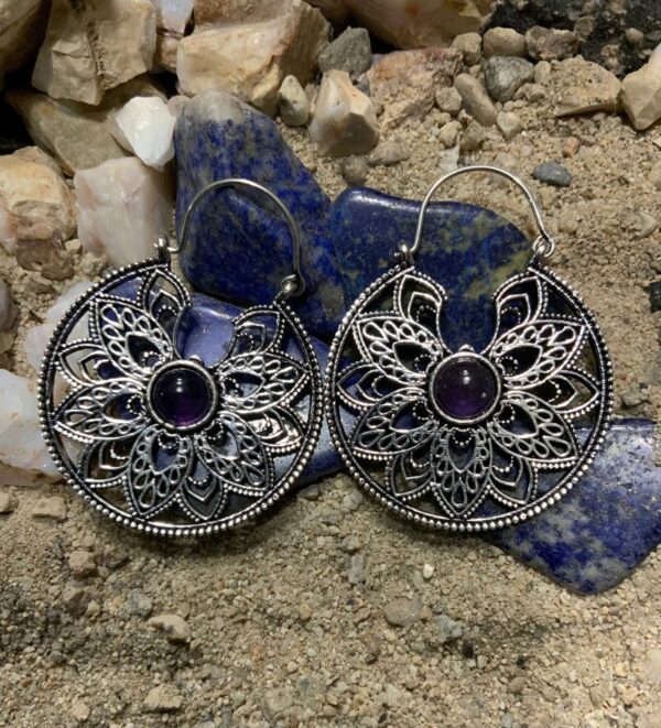 Decorative earrings placed on natural stone backdrop